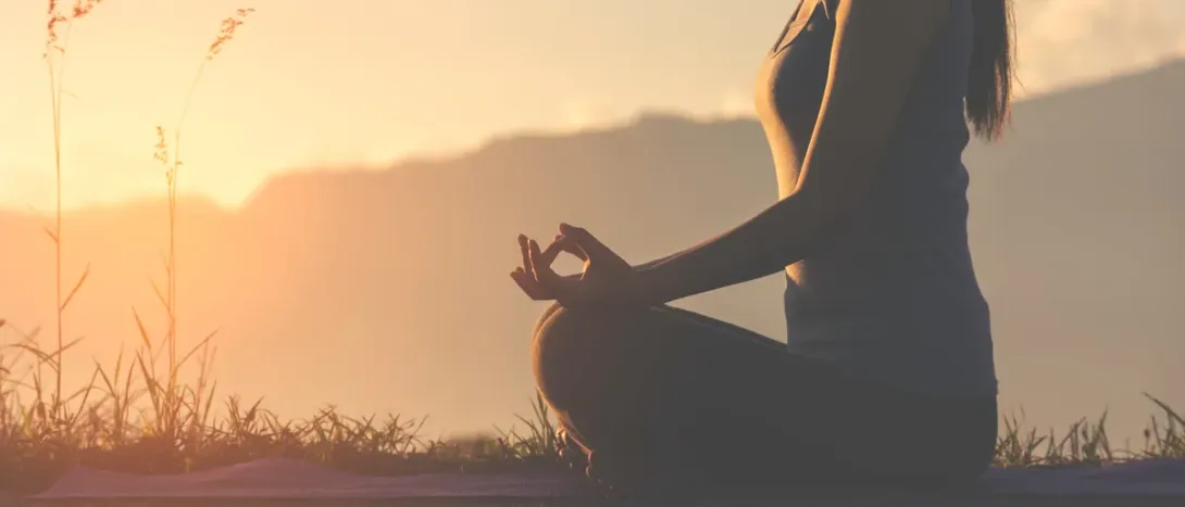 A woman sitting cross-legged at sunset