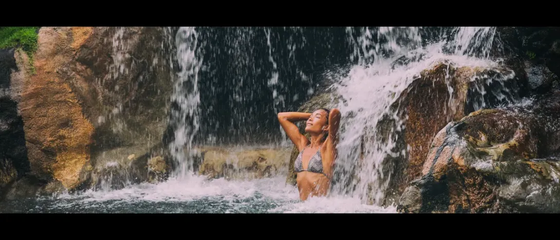 A woman standing under a waterfall