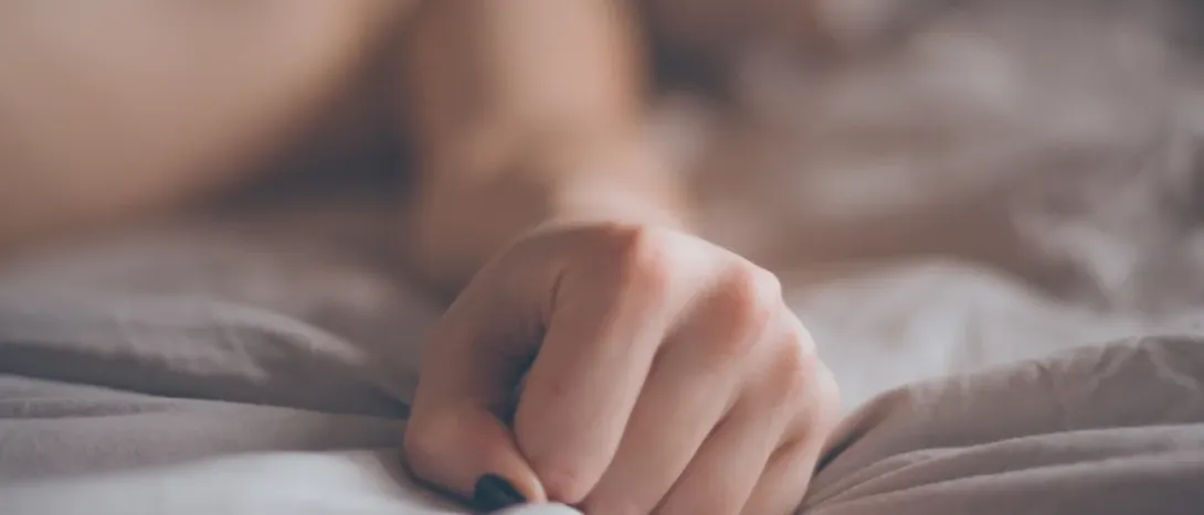 A hand resting on soft bed linen