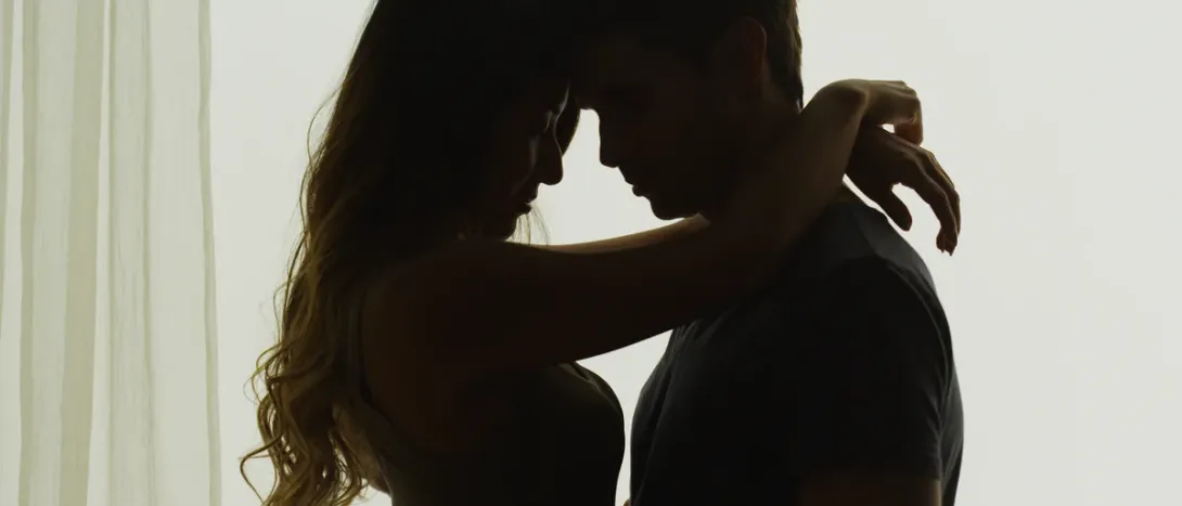 A couple's silhouette close together by a window