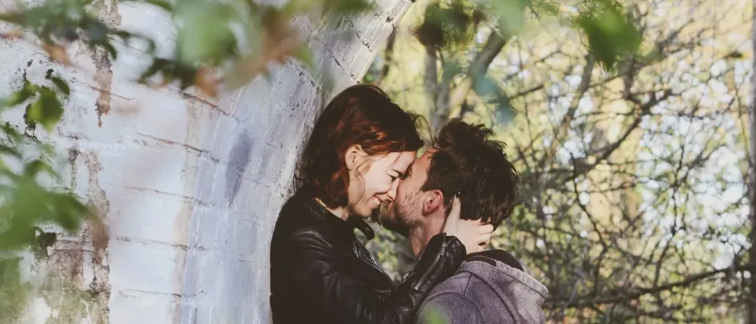 A couple kissing against a wall