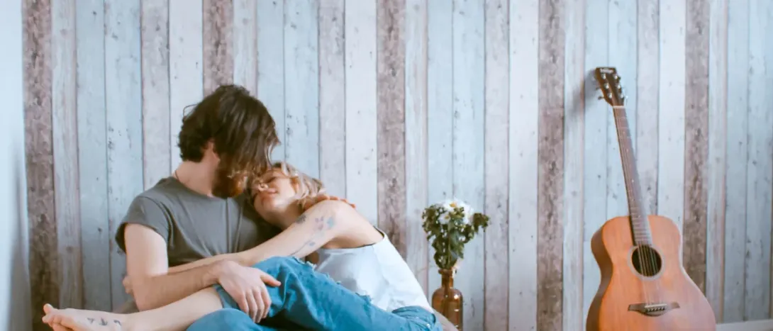 A couple relaxing together against a wooden wall