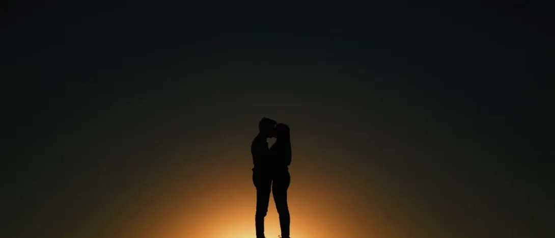 A couple's silhouette under a single light at night
