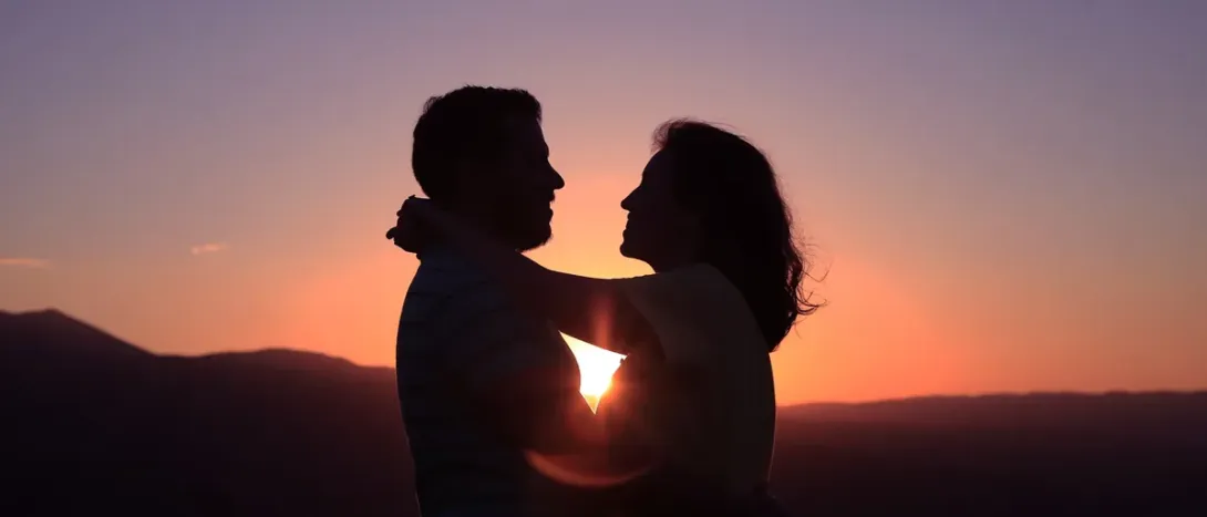 A couple facing each other at sunset