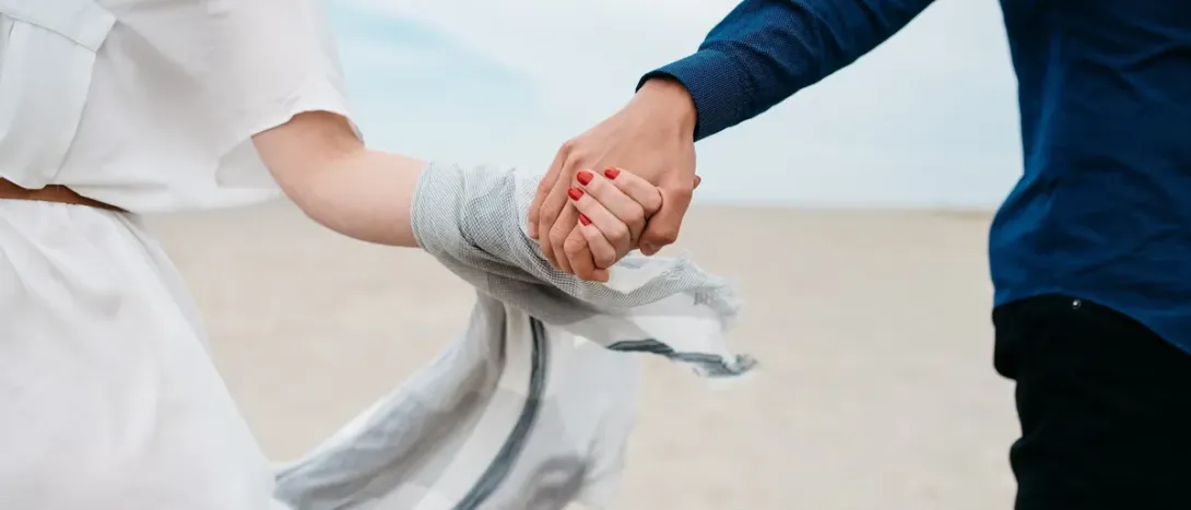 Two people holding hands on a beach