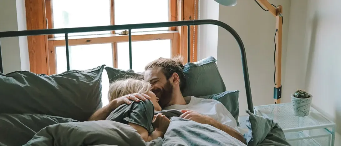 A couple lying together in a sunny bedroom