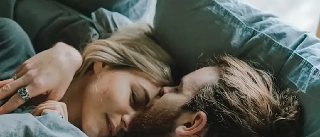 A couple lying face to face under a blanket