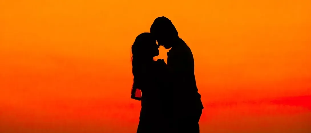 A couple's silhouette against an orange sky