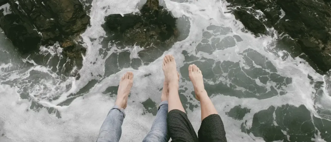 Bare feet in white surf on a rocky shore