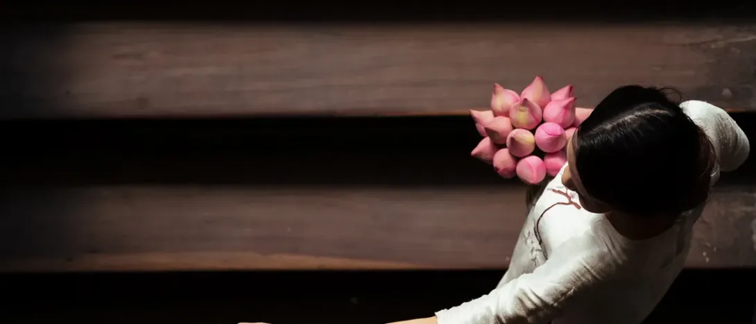 A woman lying down holding pink flowers above her