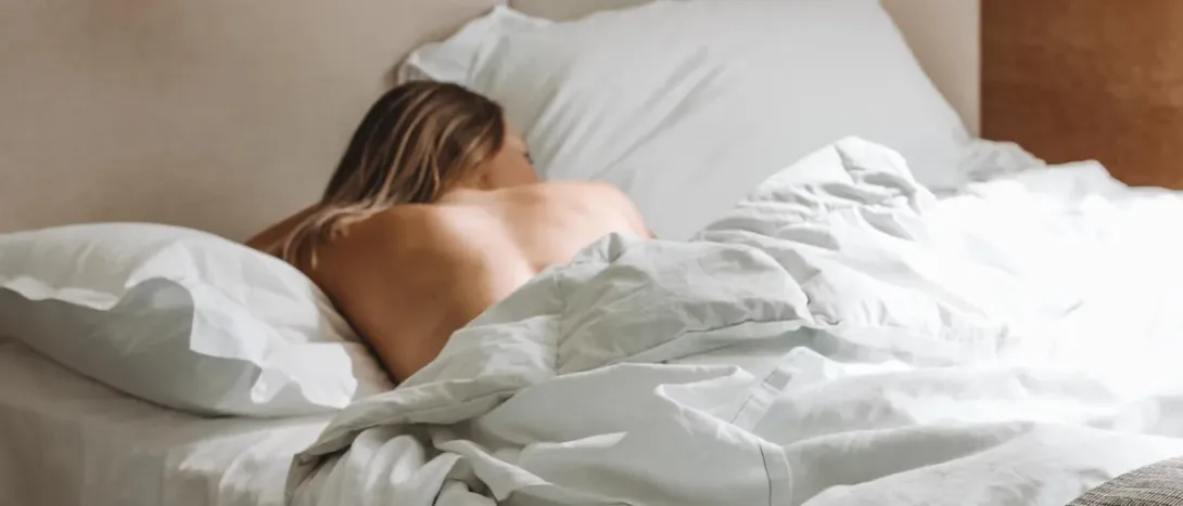A woman lying on her front among white sheets