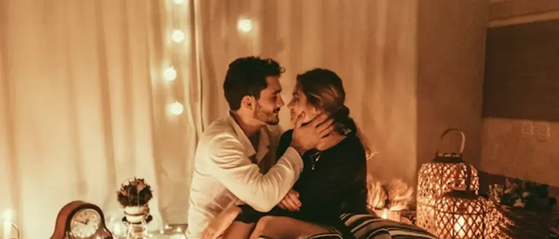 A couple sitting close in a room lit by warm lamps